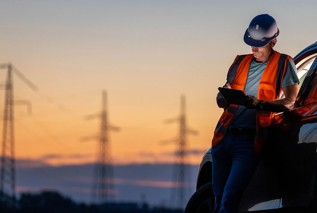 Engineer leaning against commercial van while working during sunset
