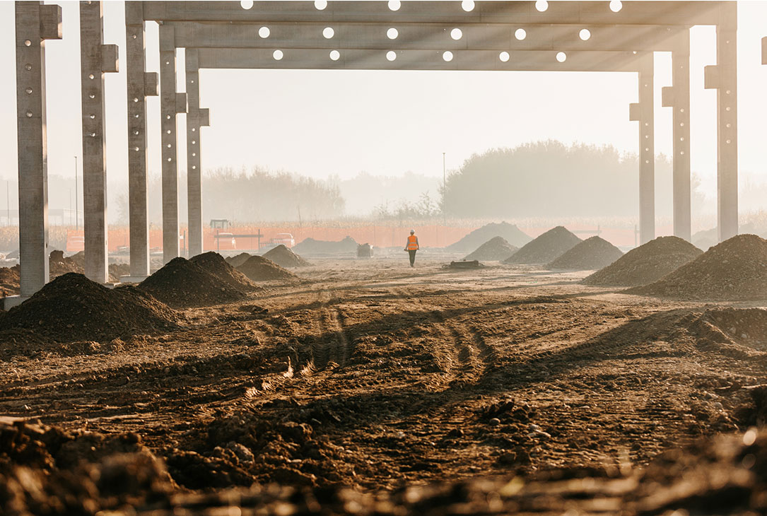 Building frame on rural landscape with female construction worker walking in the distance